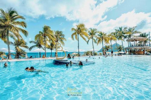 people in a swimming pool at a resort with palm trees at 913 Sweety Diamond View in Le Diamant