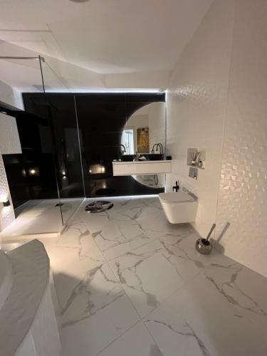 Un baño con suelo de mármol blanco y lavabo. en ESPECTACULAR Hogar en la playa MARBELLA, en Marbella