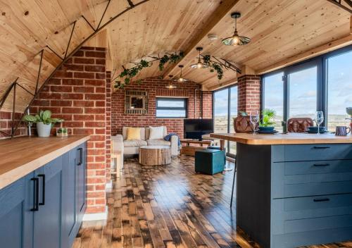 an open kitchen and living room with a brick wall at Brick Barn - Luxury Barn Conversion by River Avon in Cropthorne
