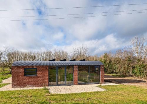 a brick building with a solar roof on a field at Brick Barn - Luxury Barn Conversion by River Avon in Cropthorne