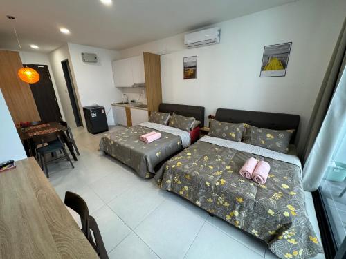a room with two beds and a table and a kitchen at The Podium, Kuching in Kuching