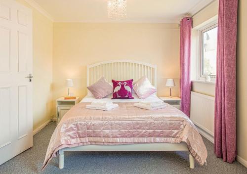 a bedroom with a large bed with pink pillows at Central 2 Bed House w/ Garden and Free Parking! in Cheltenham