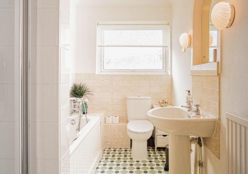 a white bathroom with a toilet and a sink at Central 2 Bed House w/ Garden and Free Parking! in Cheltenham