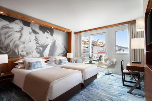 two beds in a hotel room with a large mural at JW Marriott Cannes in Cannes