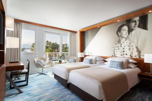 two beds in a hotel room with a poster on the wall at JW Marriott Cannes in Cannes