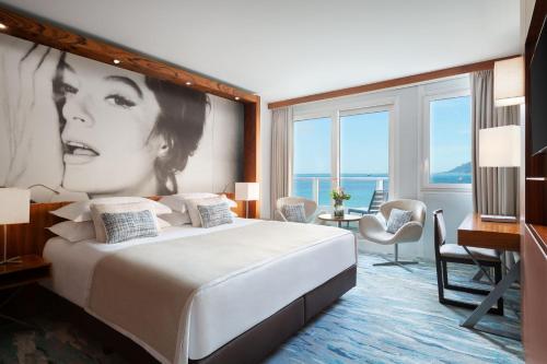 a hotel room with a large bed with a picture of a woman at JW Marriott Cannes in Cannes