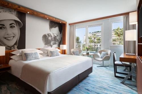 a hotel room with a bed and a portrait of a woman at JW Marriott Cannes in Cannes