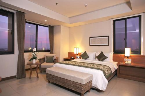 a hotel room with a large bed and windows at Axia South Cikarang Service Apartment in Cikarang