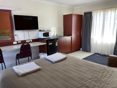 a hotel room with a bed with two towels on it at Homestead Motel in Dubbo