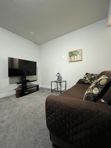 a living room with a couch and a flat screen tv at Arriva Homestay in Calgary