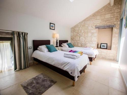 a bedroom with two beds and a stone wall at Gites de Saint Maurin in Monjoi
