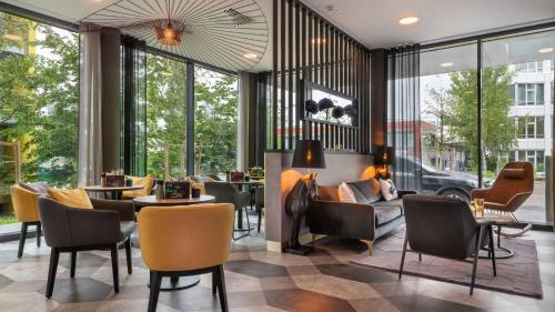 a lobby with chairs and tables and windows at Holiday Inn - the niu, Fury Aschheim Messe by IHG in Aschheim