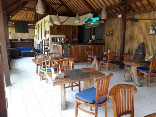 a dining room with wooden tables and chairs at Koji Garden Huts in Nusa Lembongan
