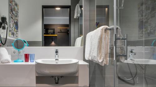a white bathroom with a sink and a shower at Holiday Inn - the niu, Fury Aschheim Messe by IHG in Aschheim