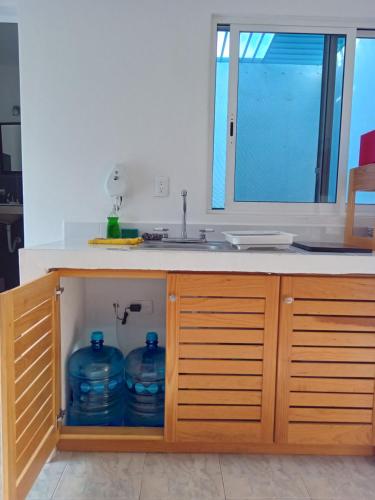 a kitchen with a sink with two blue water containers at Estudio Coatí Azul en la Isla de Cozumel en el Caribe in Cozumel