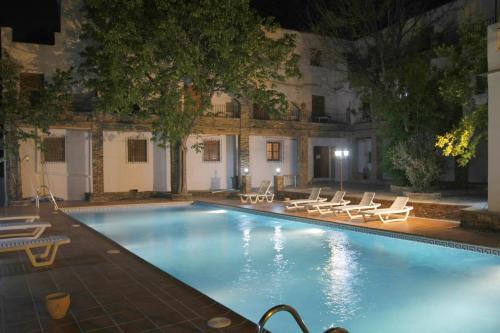 a swimming pool at night with lounge chairs around it at Hostal Rural Poqueira in Capileira