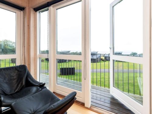 a screened in porch with a leather chair and windows at Well-maintained holiday home in Faborg in Nabbe