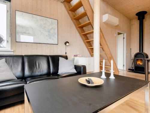 a living room with a black leather couch and a table at Well-maintained holiday home in Faborg in Nabbe
