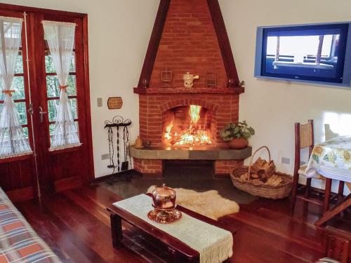 a living room with a brick fireplace in a room at Chalés Recanto da Fonte Monte Verde - MG in Monte Verde