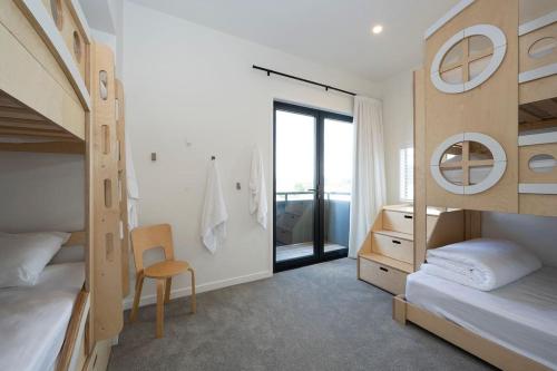 a bedroom with two bunk beds and a desk and a chair at The Big Light House'24 Home of Year in Snells Beach