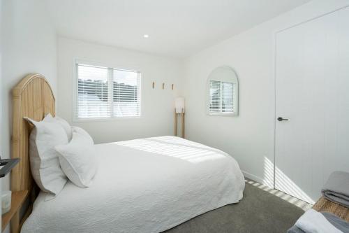 a white bedroom with a large white bed with white pillows at The Big Light House'24 Home of Year in Snells Beach