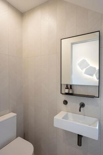 a white bathroom with a sink and a toilet at The Big Light House'24 Home of Year in Snells Beach