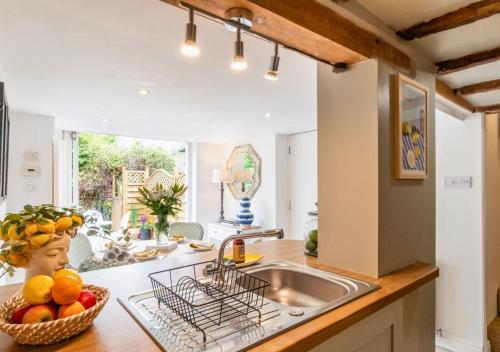 a kitchen with a sink and a bowl of fruit on the counter at Poppy Cottage - Cosy 2 Bedroom, Perfect for Family! in Shottery