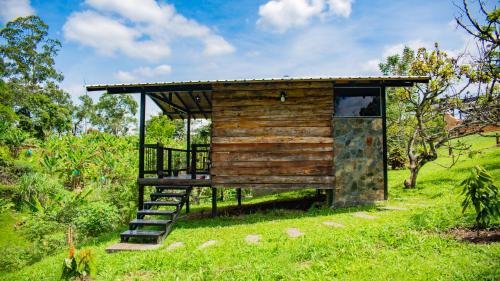 a wooden building with a staircase in a field at Paraíso familiar en el corazón del eje cafetero in La Tebaida