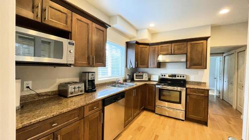 a kitchen with wooden cabinets and stainless steel appliances at James house J&J Chilliwack in Chilliwack