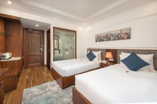 a hotel room with two beds and a desk at The Sail Hotel - My Khe Beach in Da Nang