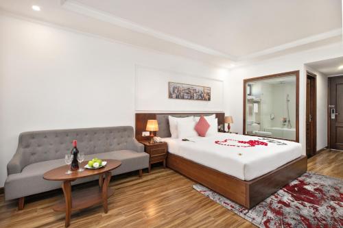 a hotel room with a bed and a couch at The Sail Hotel - My Khe Beach in Da Nang