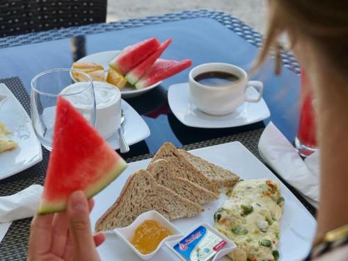 a person eating a plate of food with watermelon and a cup of coffee at Villa Umi Panglao Resort in Panglao