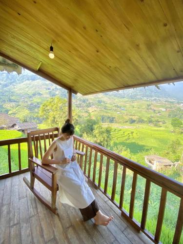 a woman sitting on a bench on a balcony at Toce House Tả van in Sa Pa