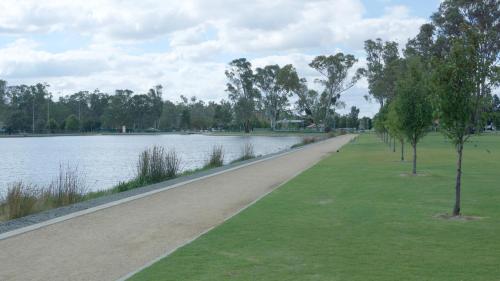 a path next to a body of water with trees at Maude St Apartments in Shepparton