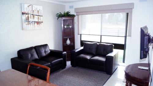 a living room with two leather chairs and a table at Maude St Apartments in Shepparton