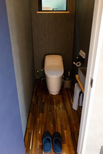 a small bathroom with a toilet and two pairs of shoes at Haru in Goto