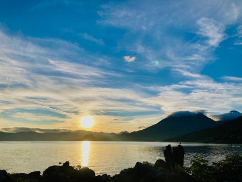 a sunset over a body of water with mountains at Casa Rosita! Vista al lago! in San Pedro La Laguna