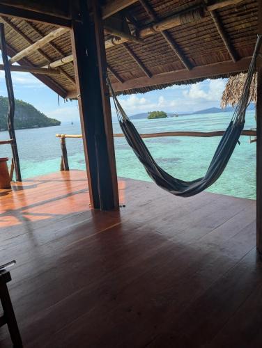 a hammock on a deck with a view of the ocean at Friwen Mangrove Eco Lodge in Yennanas Besir