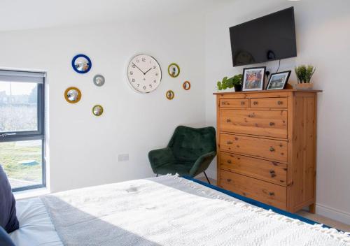 a bedroom with a dresser and a clock on the wall at Discovery Barn - Luxury 2 Bed Barn Conversion! in Cropthorne