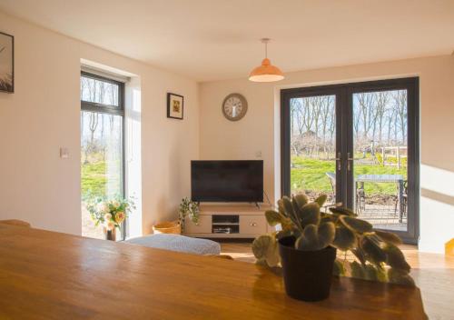 a living room with a television and a potted plant at Discovery Barn - Luxury 2 Bed Barn Conversion! in Cropthorne