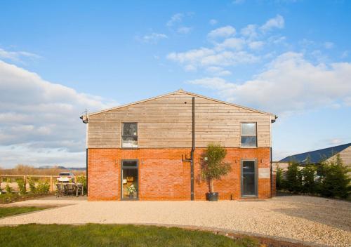 a brick house with a tree in front of it at Discovery Barn - Luxury 2 Bed Barn Conversion! in Cropthorne