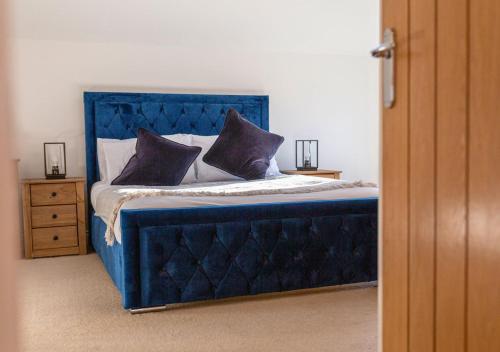 a blue bed with pillows on it in a bedroom at Discovery Barn - Luxury 2 Bed Barn Conversion! in Cropthorne