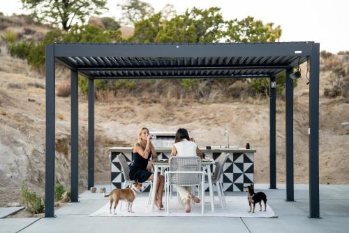 two women sitting at a table with their dogs at Whistling Rock By The Cohost Company in Yucca Valley Service Center Heliport