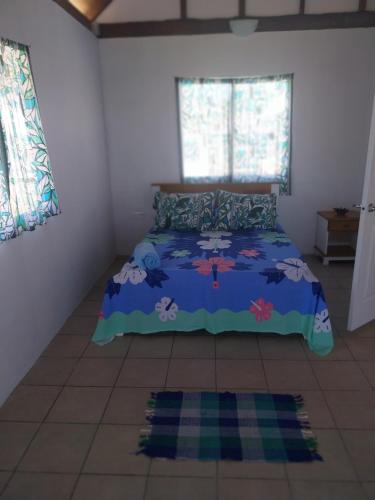 una camera da letto con un letto con un piumone blu di Vaimoe Lodge Tiputa a Tiputa