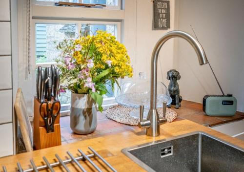 a kitchen counter with a sink and a vase of flowers at Diston's Lane - Beautiful 2BD Home, Perfect For Family Retreat! in Chipping Norton