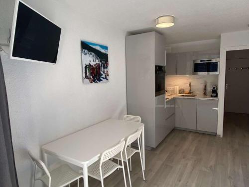 - une table et des chaises blanches dans une petite cuisine dans l'établissement Coquet studio coeur station pour 4, proche commerces et pistes - FR-1-322-655, aux Orres
