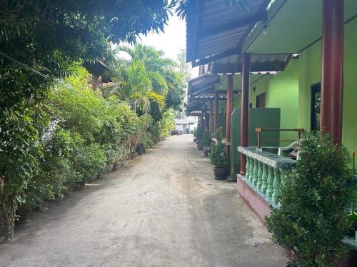 a dirt road in front of a green building at ABC Bungalow in Baan Tai