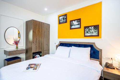 a bedroom with a large white bed and a yellow wall at Dream Premium Hotel & Spa in Hanoi