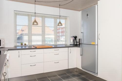 a kitchen with white cabinets and a refrigerator at Large Townhouse Centrally Located In Ebeltoft in Ebeltoft