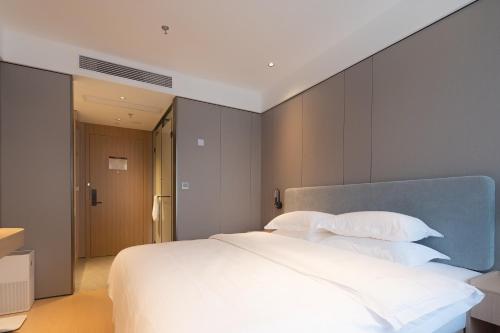 a bedroom with a large bed with white sheets and pillows at Dayin Garden Hotel -People's Square & Nanjing Road-Large Social Area -Bar -Café -Gym -Free Laundry Luggage Storage -24H Front Desk-English Service in Shanghai